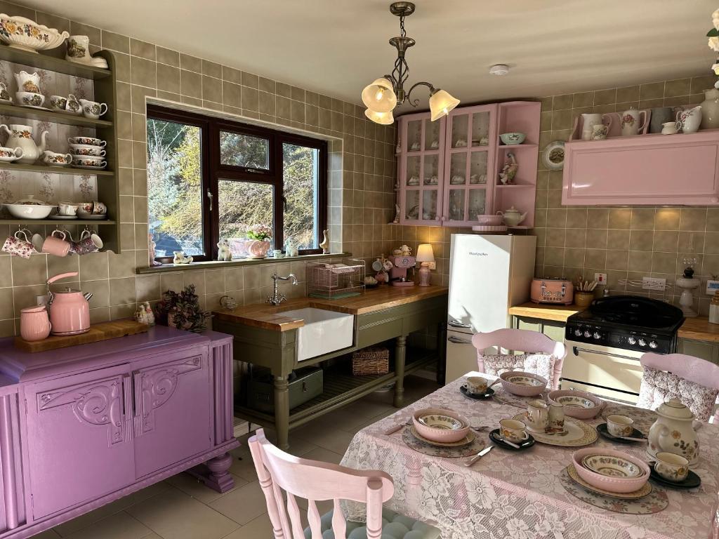 a kitchen with purple cabinets and a table with chairs at Memory Lane Farmhouse Carlingford in Lubhaidh