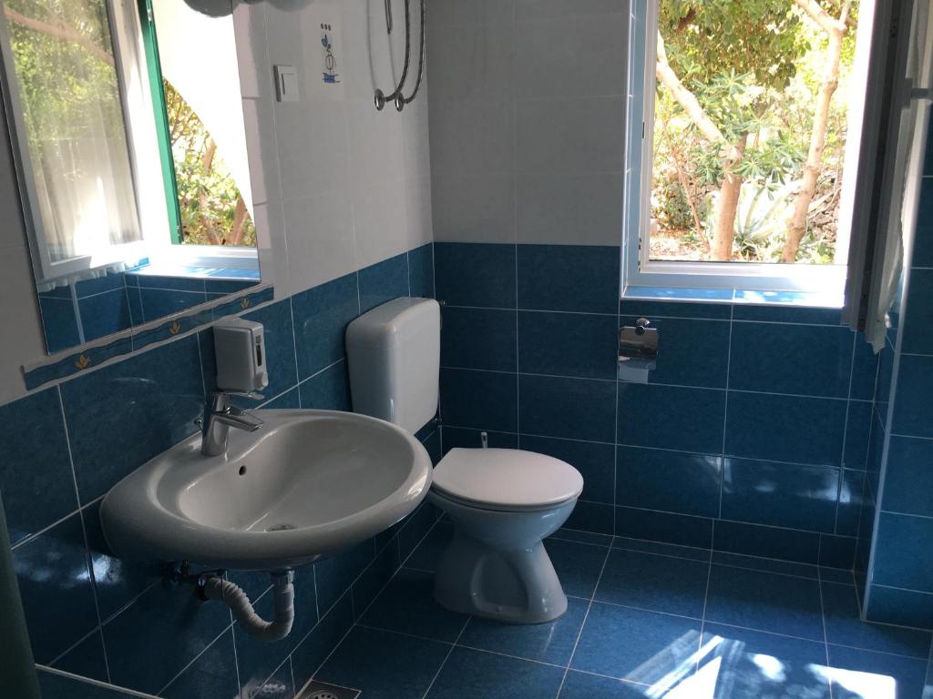a blue tiled bathroom with a toilet and a sink at Apartments MiaMaja in Novalja