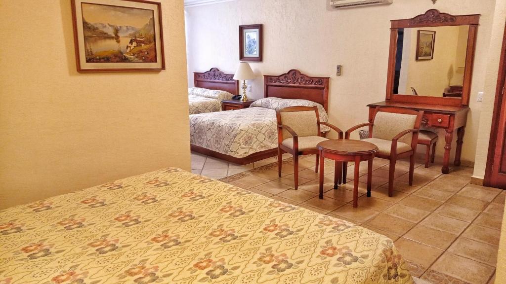 a hotel room with two beds and a table and chairs at Hotel Vista Hermosa in Cuernavaca