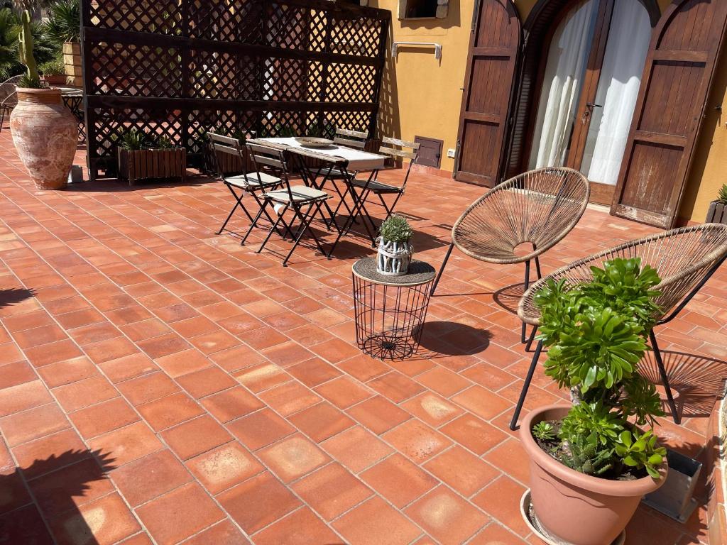 a patio with chairs and tables and potted plants at B&B La Torre in Realmonte