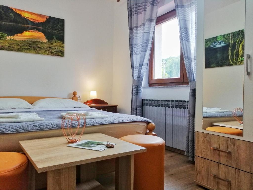 a small bedroom with a bed and a table at Guest House Končar in Plitvička Jezera