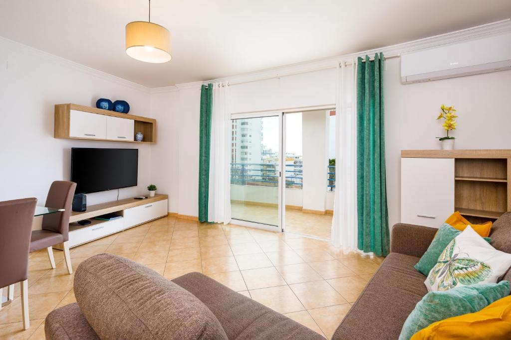 a living room with a couch and a television at Apartamento Monarquia - T3 Quarteira in Quarteira