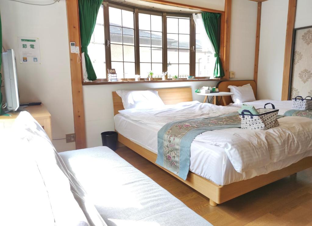 1 dormitorio con 2 camas y ventana en 日久の宿 en Kokubunji