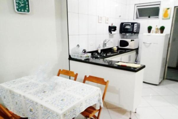 uma cozinha com uma mesa e uma mesa e cadeiras brancas em Apartamento Pé na Areia em São Bernardo do Campo
