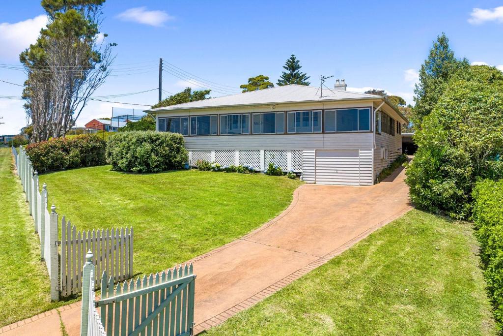 12 Bluewater Drive Narooma في ناروما: بيت ابيض مع سياج وساحة