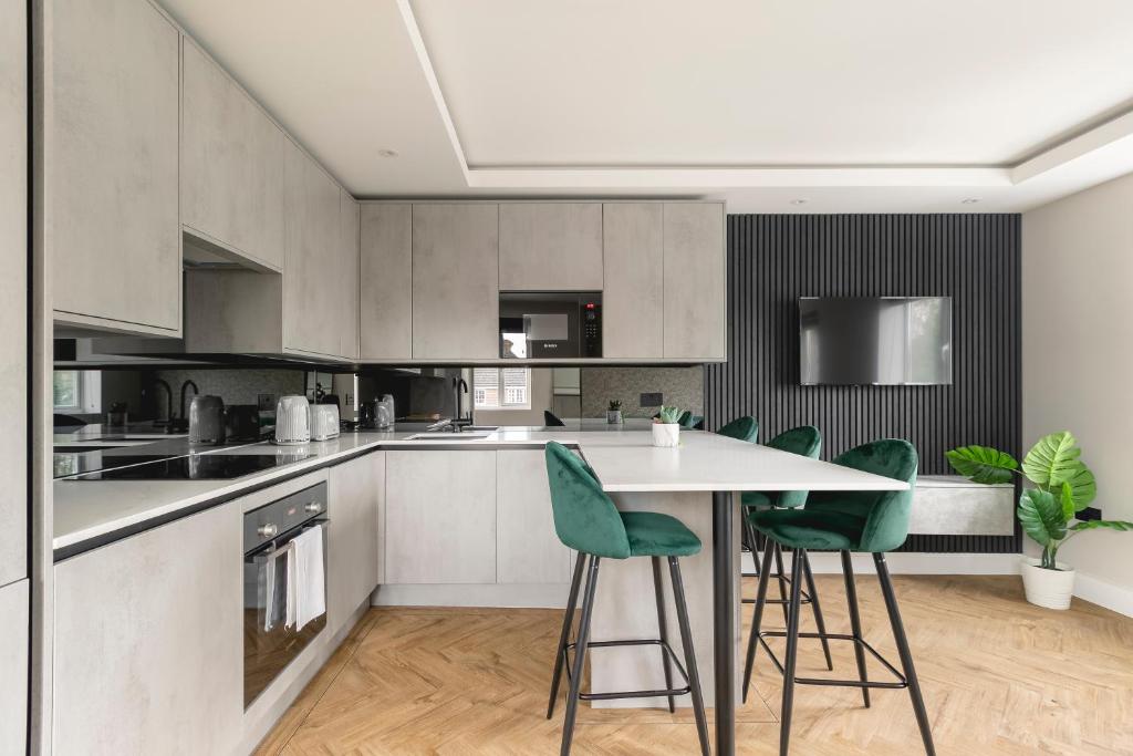 uma cozinha com uma mesa e cadeiras verdes em Skyvillion - COZY LARGE 4 Bed Apartments in London Enfield, Mins to Tube Station, Free Wi-Fi em Cockfosters