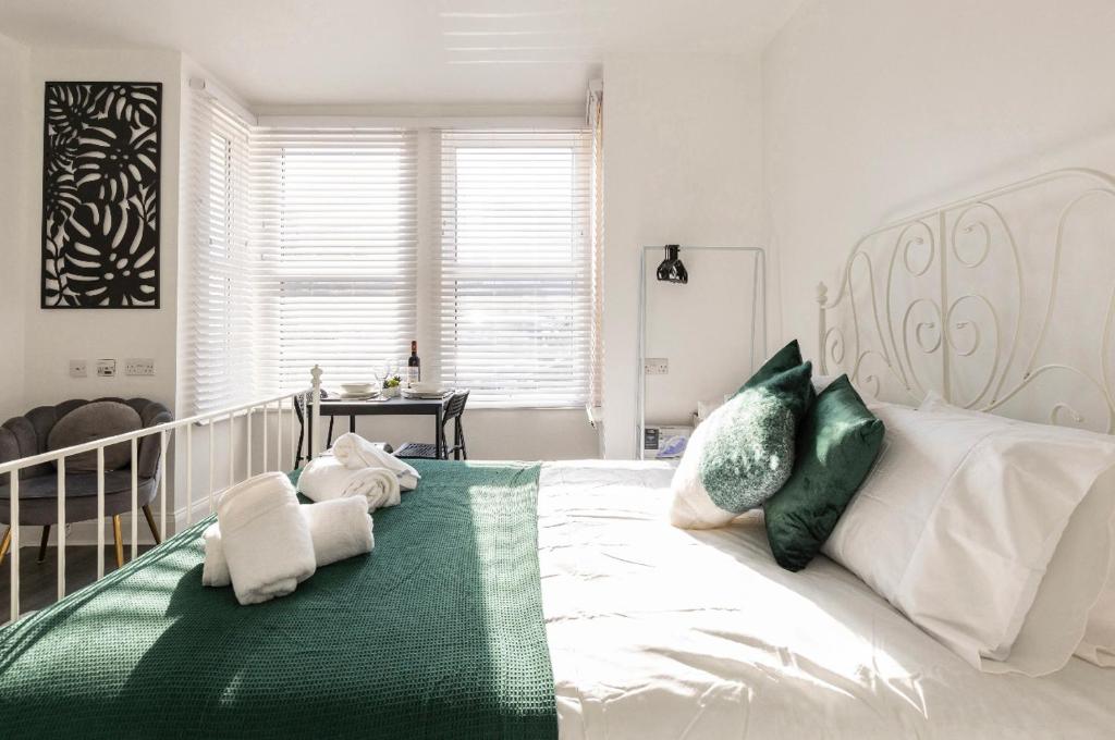 um quarto com uma grande cama branca com toalhas em New renovated studio flat with separate kitchen and bathroom em Southall