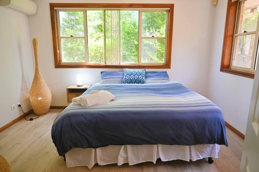 ein Schlafzimmer mit einem Bett mit blauer Decke und einem Fenster in der Unterkunft Lakeside Luxury in Gorokan