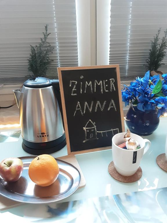 uma mesa com um prato de frutas e um bule de chá e uma placa em Zimmer Anna em Parchim
