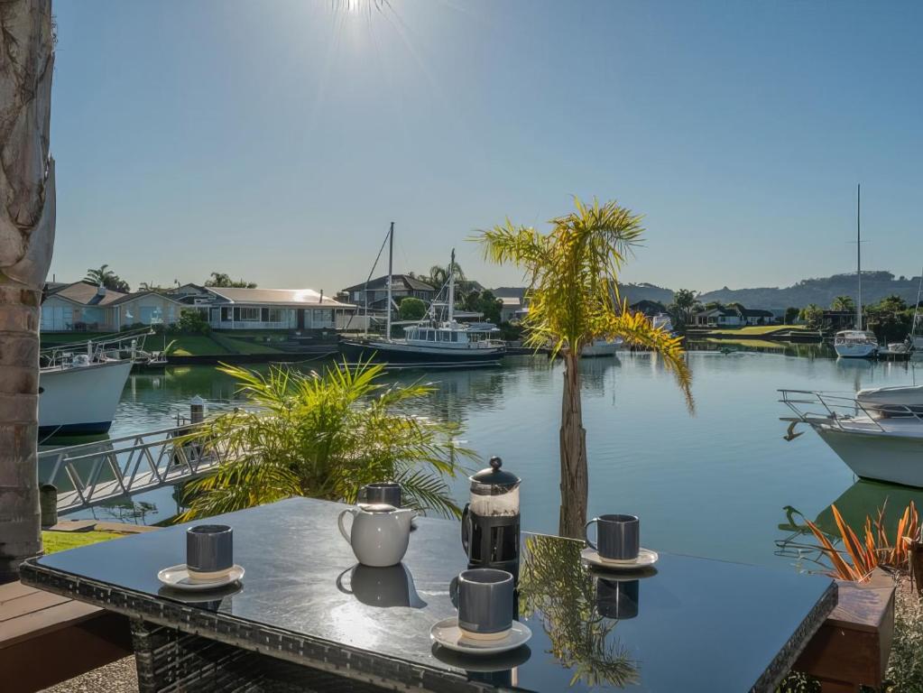 a table with a coffee maker on it next to the water at Hosts on the Coast Boost Morale on the Canal in Whitianga