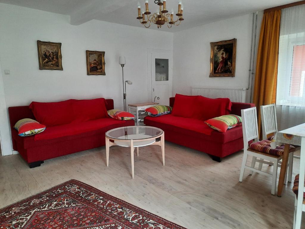una sala de estar con 2 sofás rojos y una mesa. en FeWo An der Bruecke en Solnhofen
