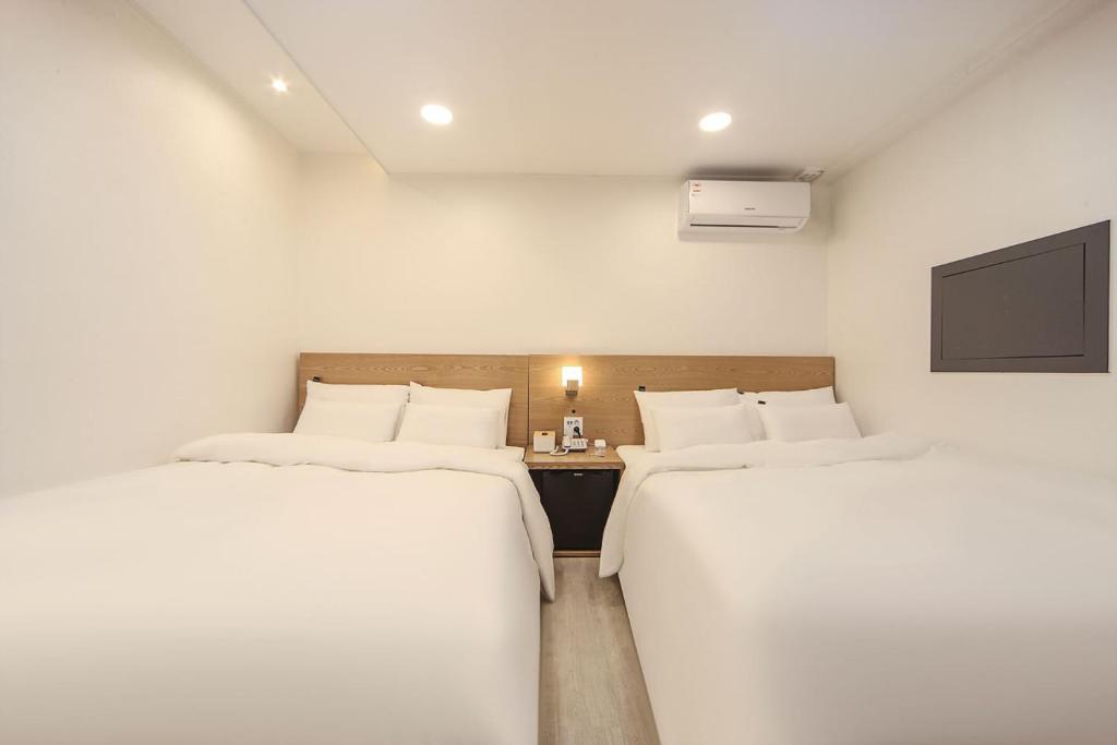 zwei Einzelbetten in einem Zimmer mit Fernseher in der Unterkunft Pier26 Hotel in Pohang