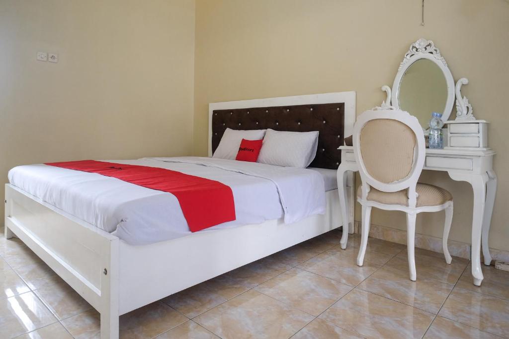 a white bedroom with a white bed and a chair at RedDoorz Syariah near Alun Alun Wonosobo 3 in Wonosobo