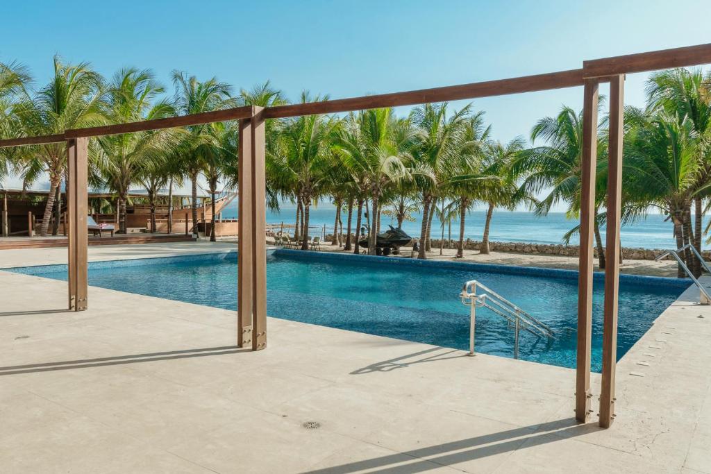 a swimming pool with palm trees and the ocean at Castillete in Cartagena de Indias