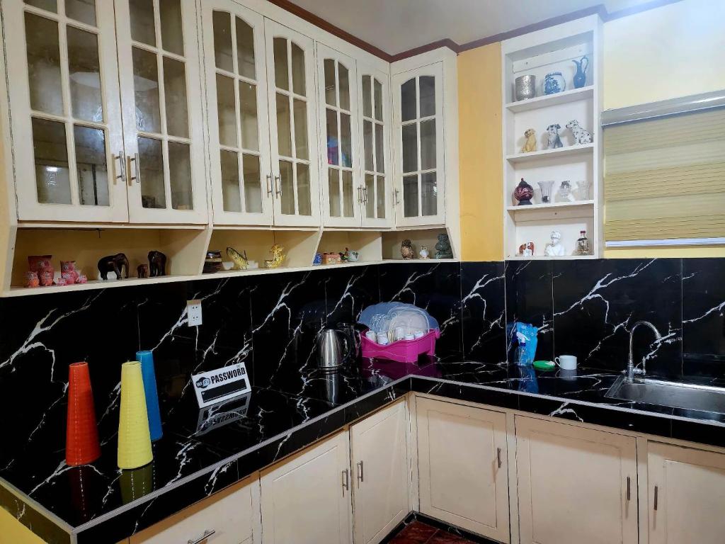 una cocina con armarios blancos y encimeras de mármol negro en D' ALORA Transient House, en Daet
