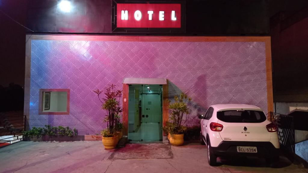 um carro branco estacionado em frente a um edifício rosa em Hotel Dalias em Guarulhos