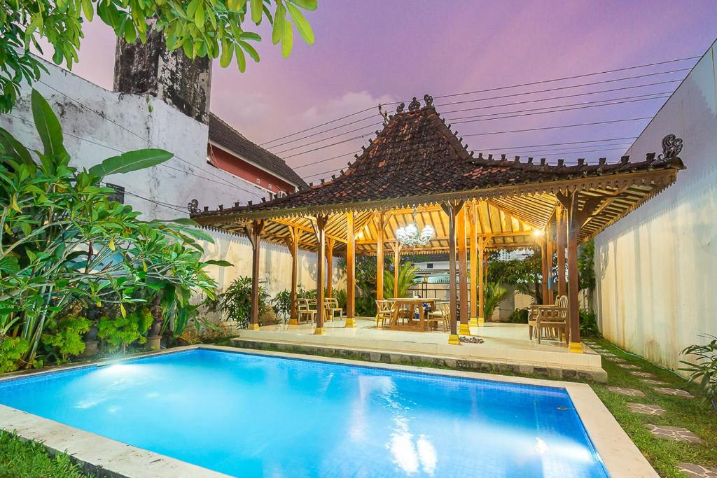 a swimming pool in front of a house with a gazebo at Villa Omah Kangen in Kejayan