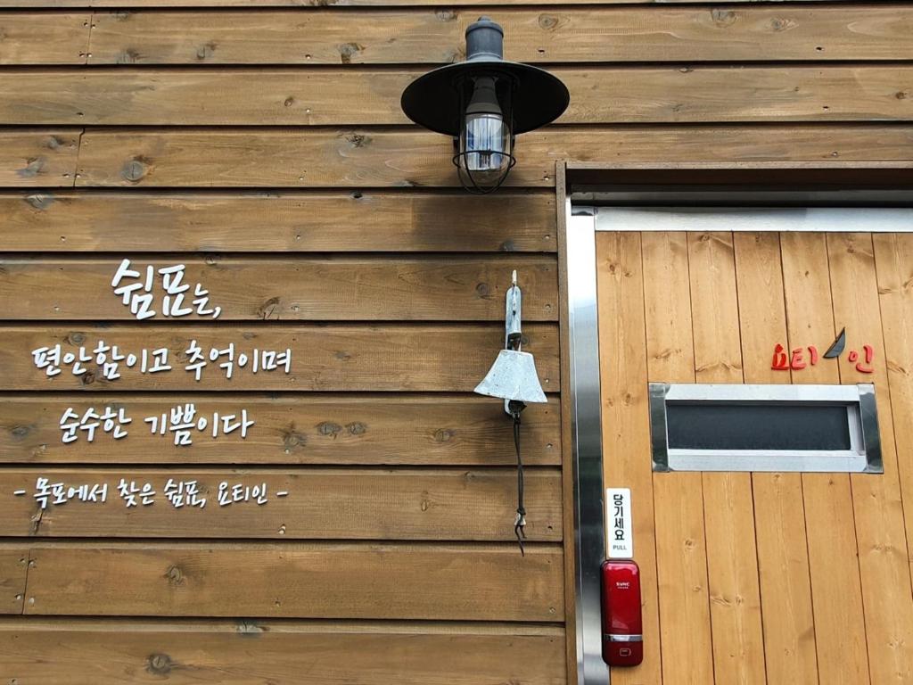 木浦的住宿－Yachtie Inn Mokpo，木墙,有灯和门