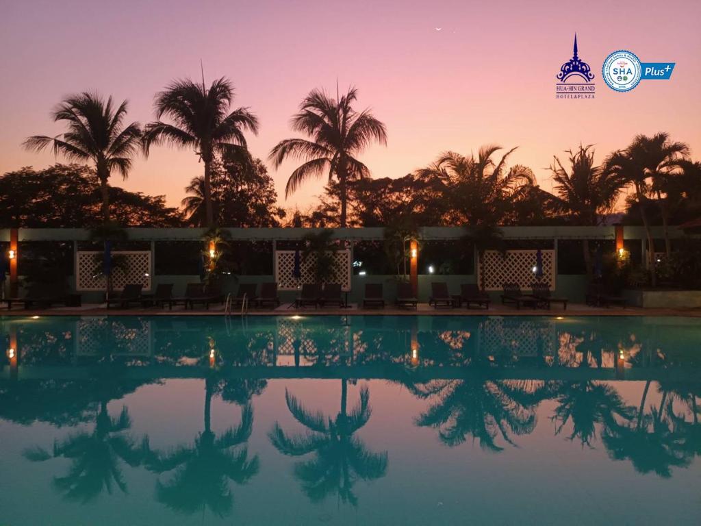 uma piscina ao pôr-do-sol com palmeiras ao fundo em Hua Hin Grand Hotel and Plaza - SHA Extra Plus em Hua Hin