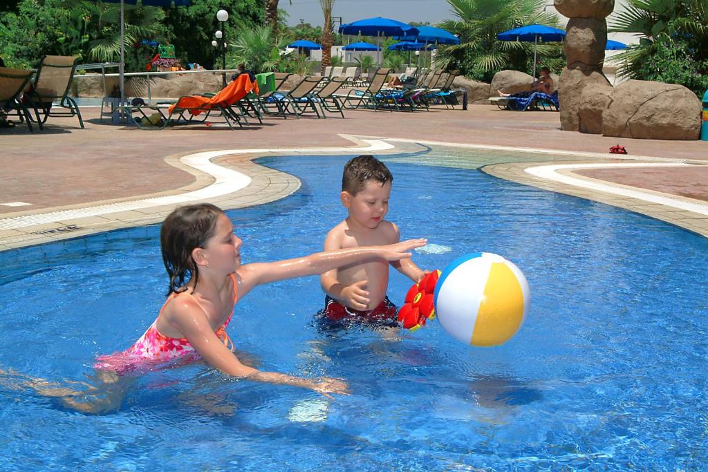 two children playing with a beach ball in a pool at Nissiana Hotel & Bungalows in Ayia Napa