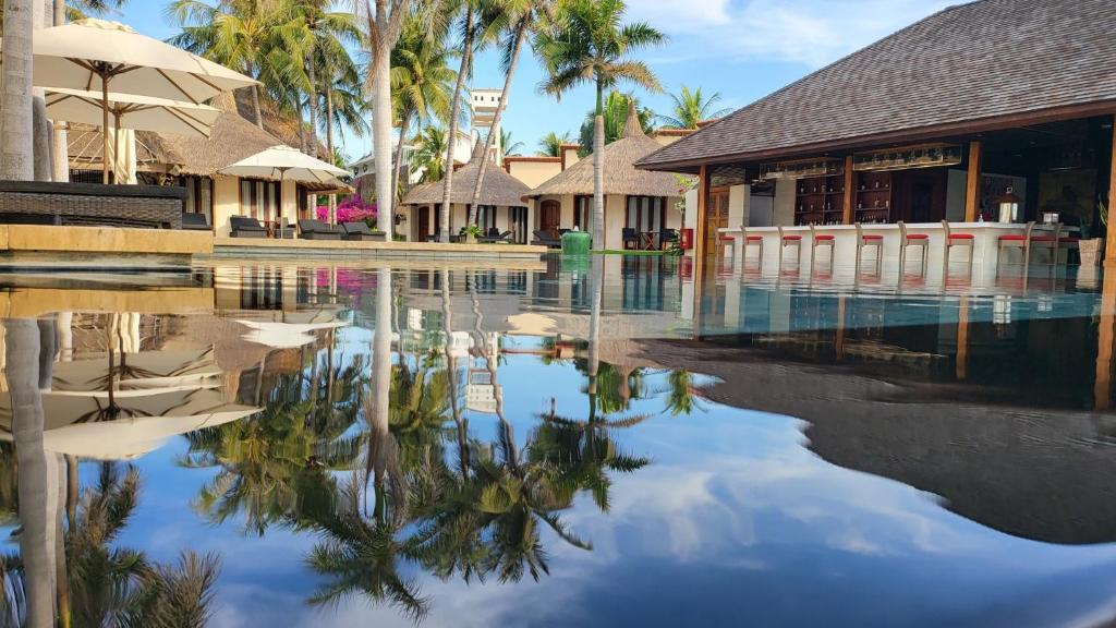 una piscina frente a un complejo con palmeras en Sunsea Resort, en Mui Ne