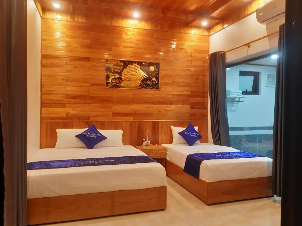 two beds in a room with wooden walls at Trang an green river homestay in Ninh Binh