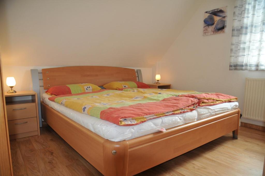 een slaapkamer met een bed met een houten frame en 2 lampen bij Haus Jodokus, Whg Professor Paljass in Kellenhusen