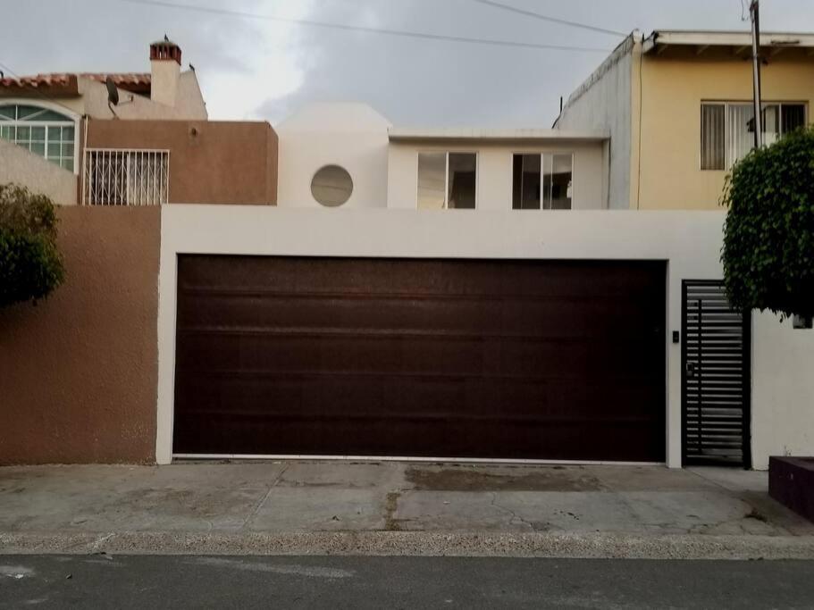 a garage with a brown garage door in front of a house at Tu Casa de Familia in Tijuana
