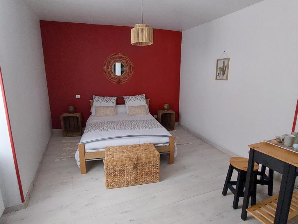 1 dormitorio con cama y pared roja en Les chambres au pied du Rey, en Sainte-Colome