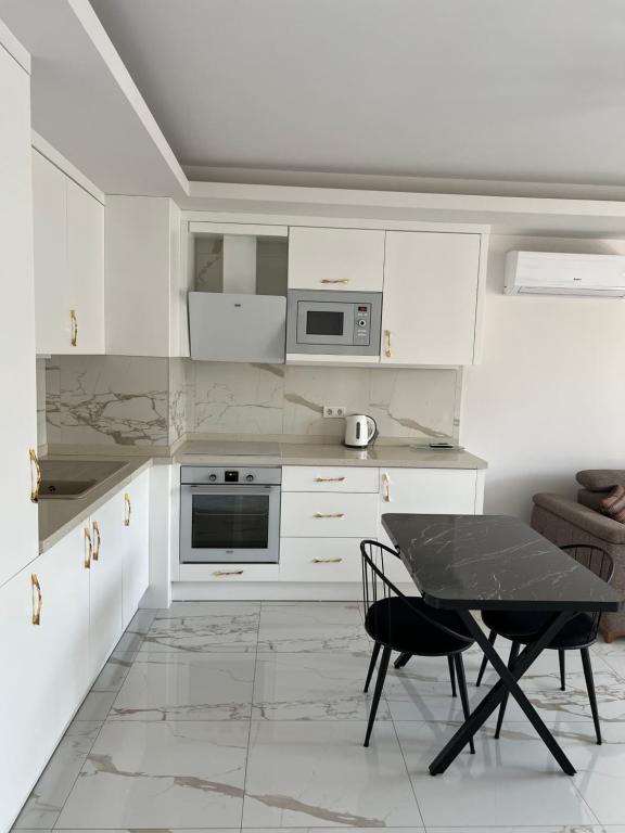 - une cuisine avec des placards blancs, une table et des chaises dans l'établissement Elite Marine Apartments, à Alanya