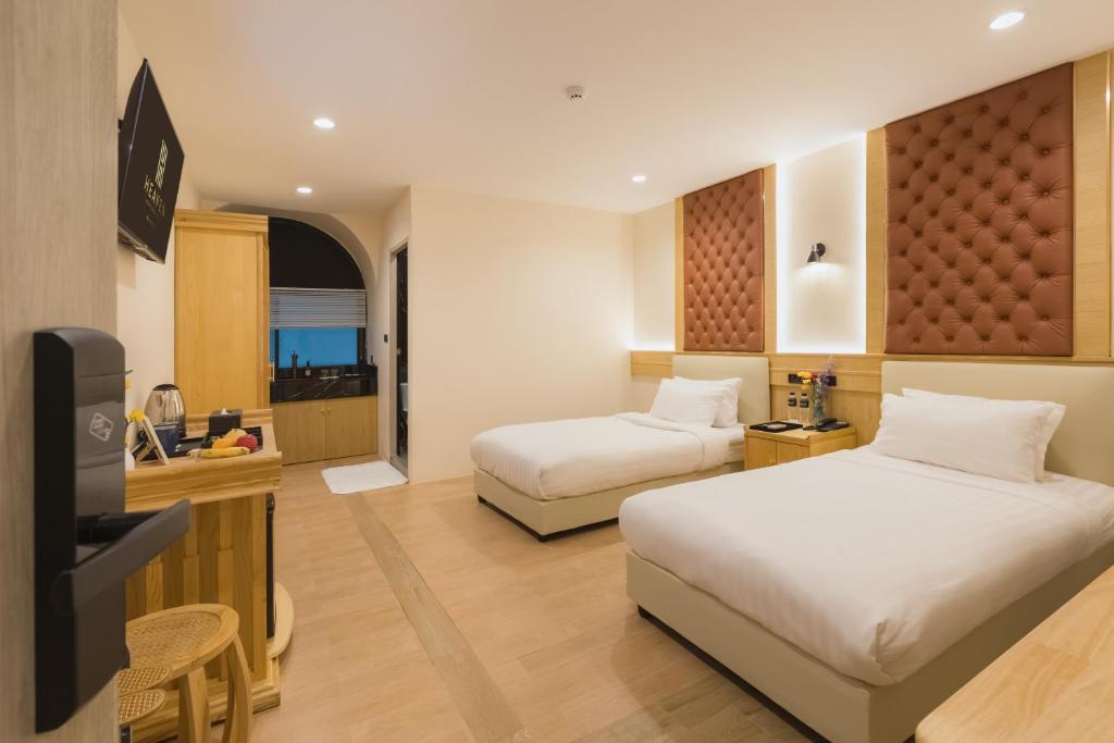 a hotel room with two beds and a flat screen tv at Heaven Boutique Hotel in Bangkok
