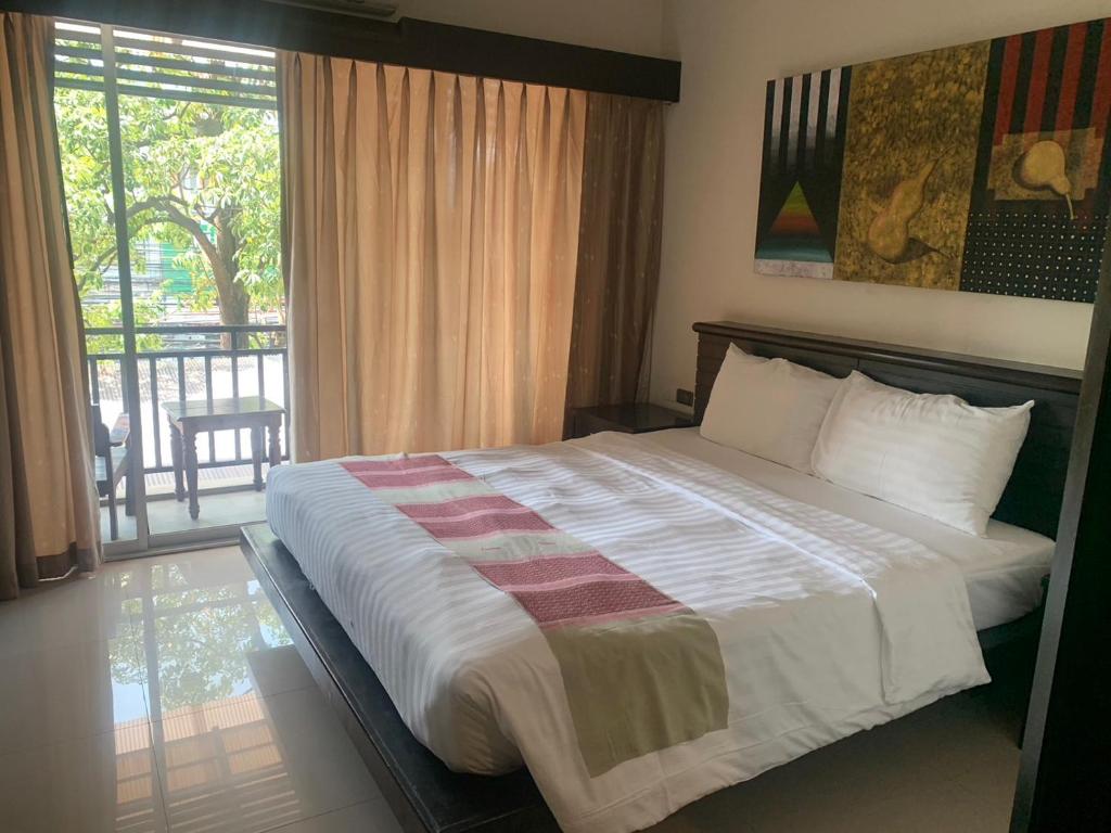 a bedroom with a large bed and a balcony at Lub Sbuy Hostel in Phuket Town