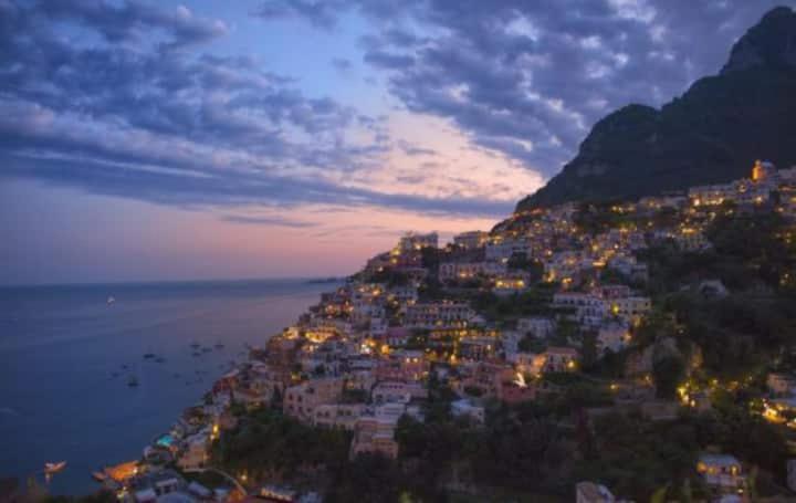 una città su una collina con l'oceano di notte di La Pigolina a Positano