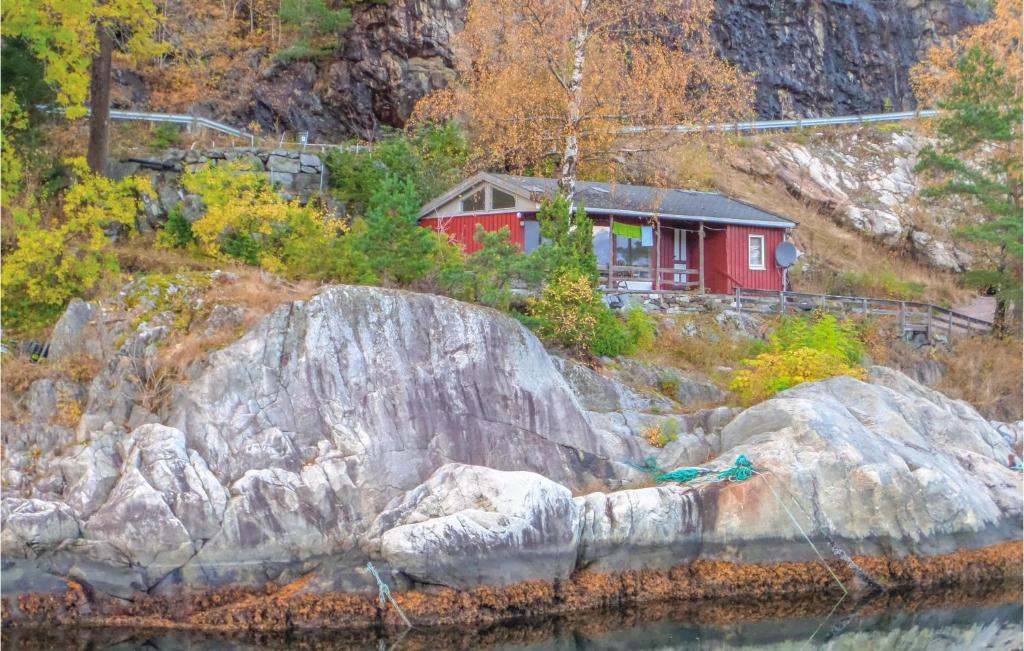 ein rotes Haus auf einem Hügel neben dem Wasser in der Unterkunft Beautiful Home In Vallavik With House A Mountain View in Bu