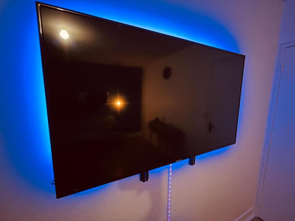 a flat screen tv hanging on a wall with blue lights at Appartement Prestige - Amiens in Amiens