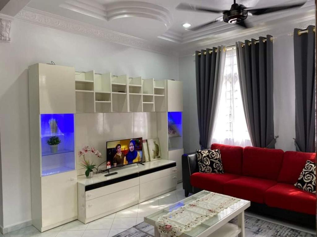 a living room with a red couch and a tv at Dahan Homestay in Kota Bharu