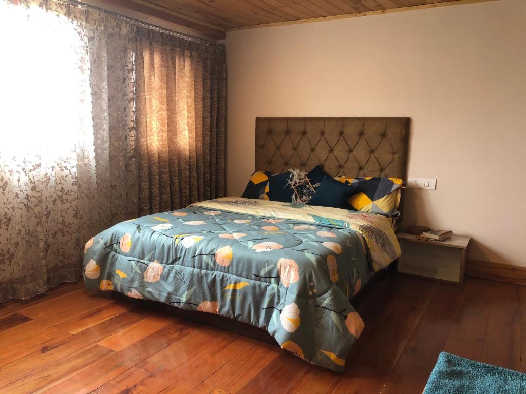 a bedroom with a bed with a comforter and a window at Hello Home in Pelling