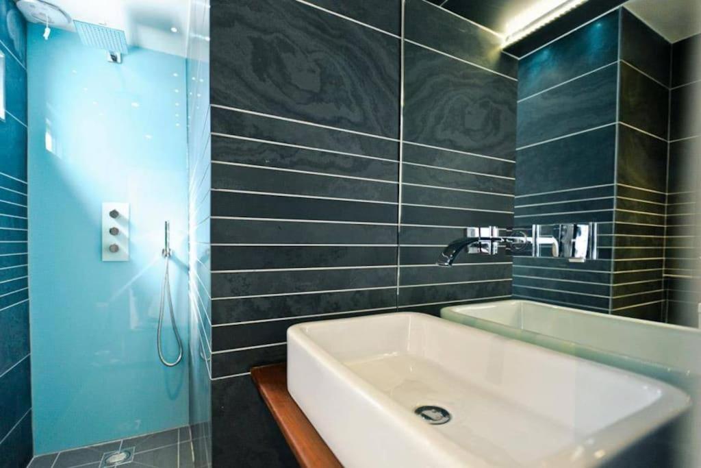 a bathroom with a white sink and a shower at Edge14- spacious, stylish and near the beach! in Newquay