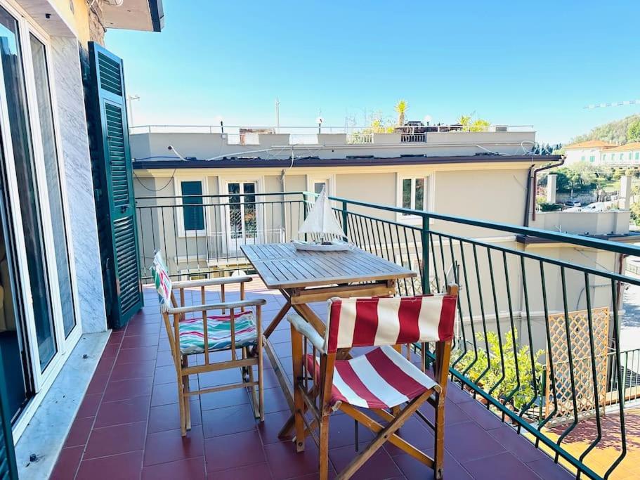 balcón con mesa de madera y 2 sillas en Casa Delfina, en Tellaro