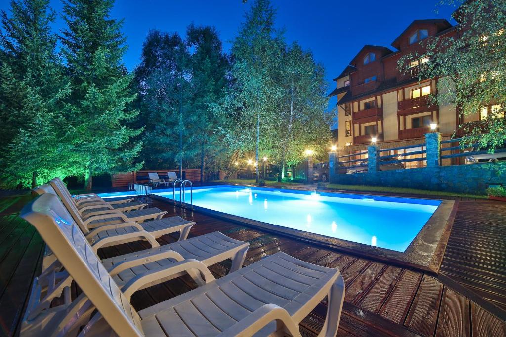 a swimming pool with lounge chairs next to a building at Hotel&SPA Jawor in Zawoja