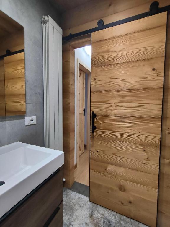 bagno con lavandino bianco e porta in legno di Piccolo Appartamento Casa Vacanze B&B Angela a Clusone