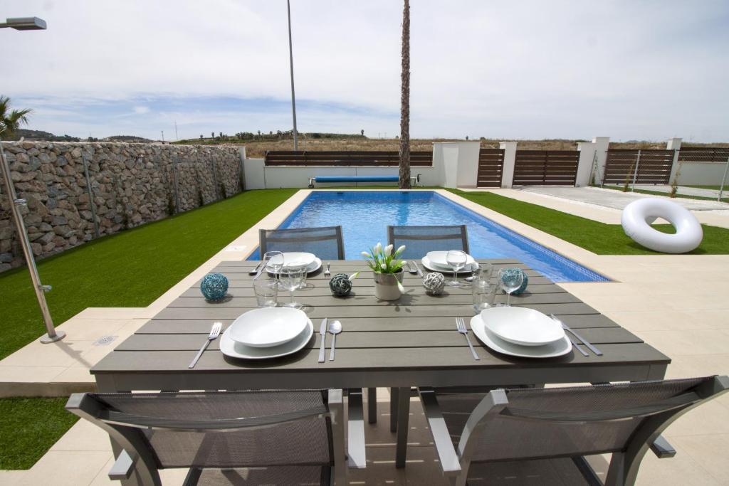 a dining table and chairs on a patio with a pool at Villa Malibu 3021 in Vistabella