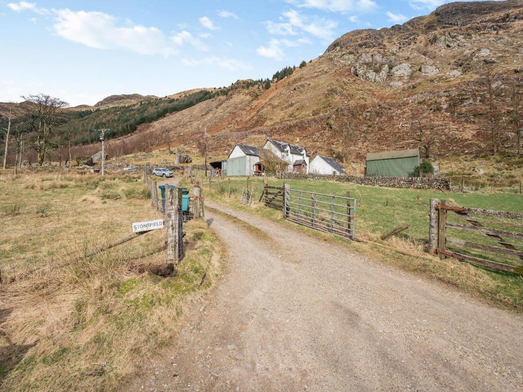 a dirt road in a field with a fence at Stonefield Farm Cottage in Benmore