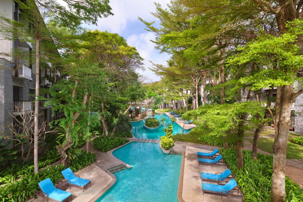 una imagen de una piscina del complejo con sillas y árboles en Courtyard by Marriott Bali Nusa Dua Resort, en Nusa Dua