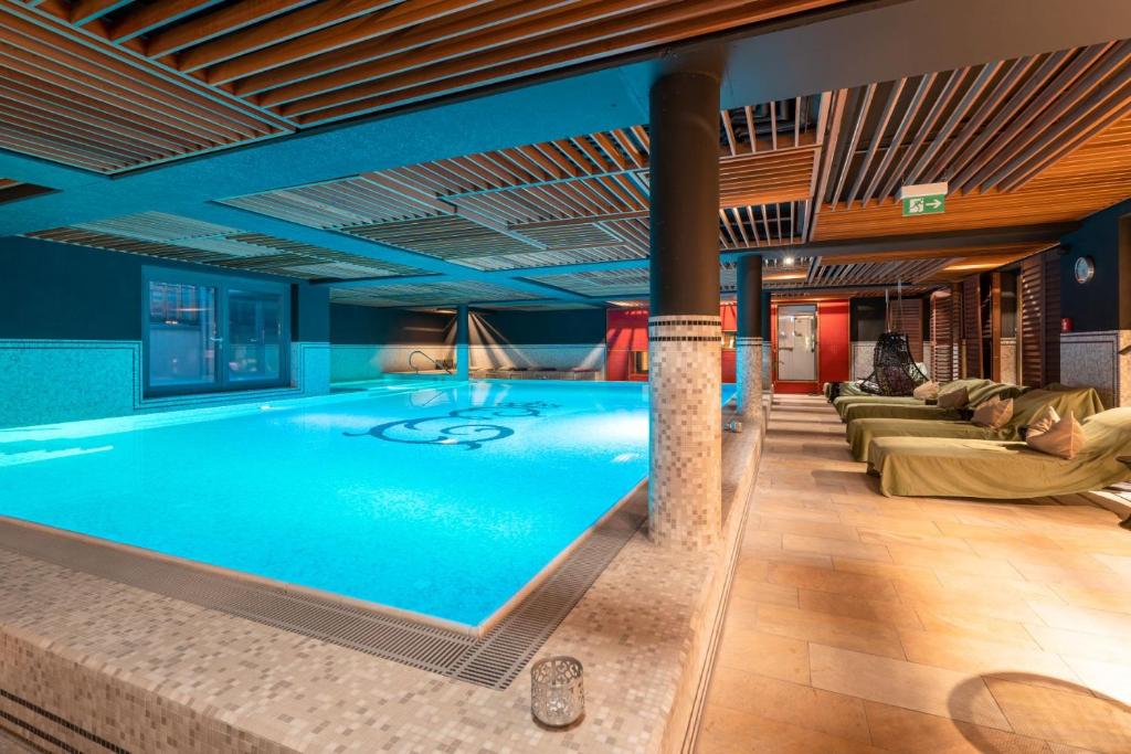 a large swimming pool in a building with couches and chairs at Hotel Erbprinz - Gourmet & Spa in Karlsruhe