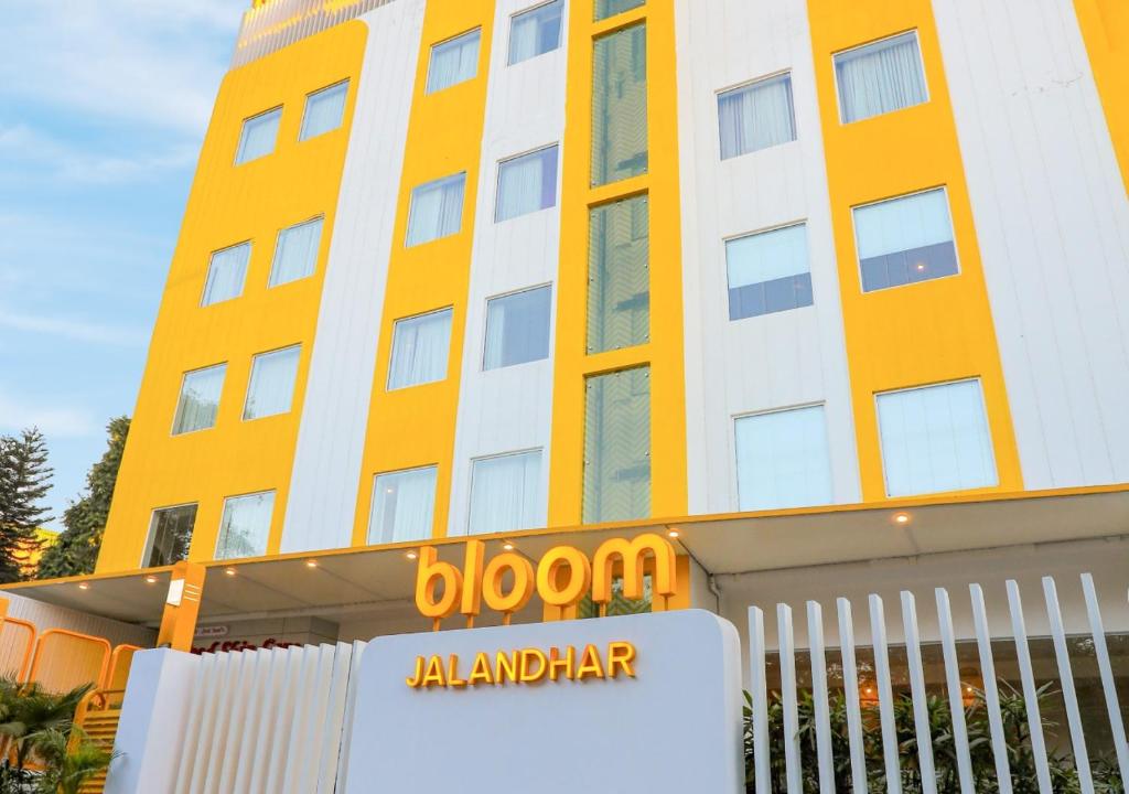 un edificio blanco y amarillo con un cartel delante en Bloom Hotel - Jalandhar, en Jalandhar