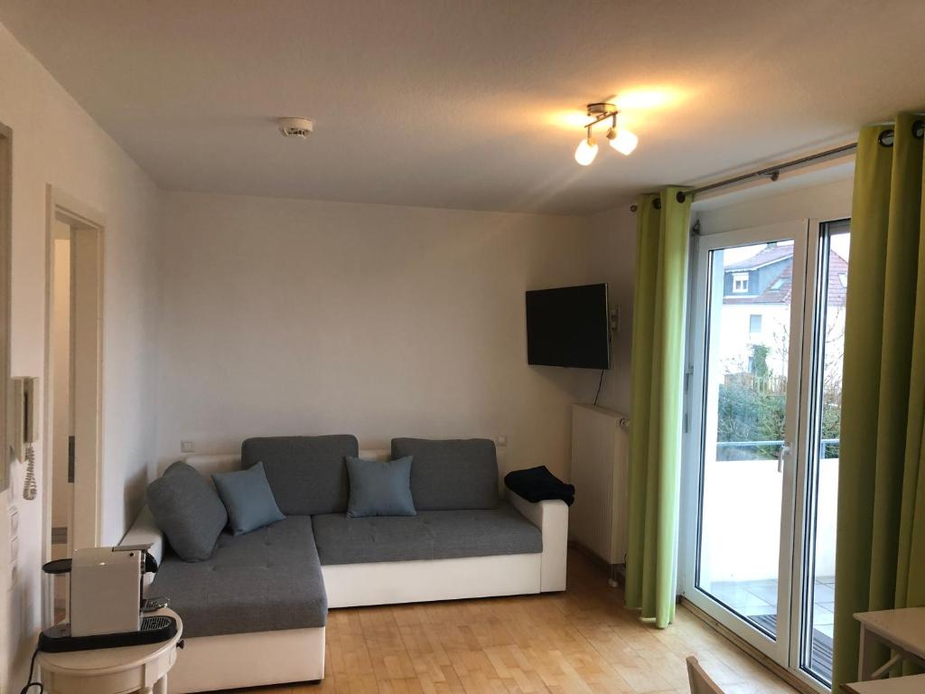 - un salon avec un canapé et une porte coulissante en verre dans l'établissement Cozy Appartment with Balcony, à Friedrichshafen