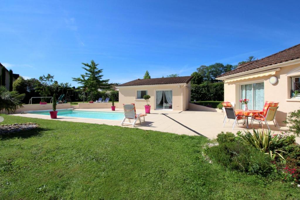 een achtertuin met een zwembad en stoelen en een huis bij Les carpes a limoges in Limoges