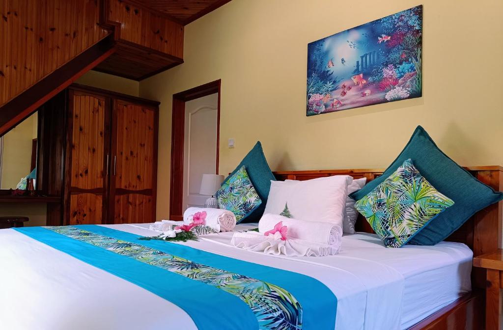 1 dormitorio con 1 cama con almohadas azules y blancas en Badamier Self-Catering en La Digue