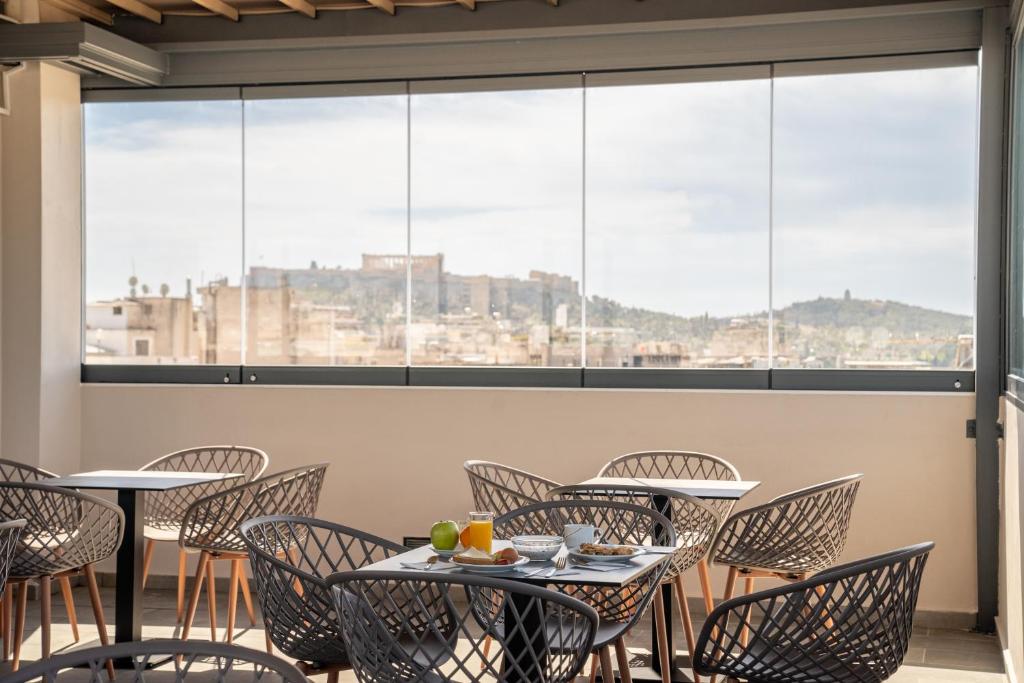 a restaurant with tables and chairs and large windows at Dunlin Hotel in Athens